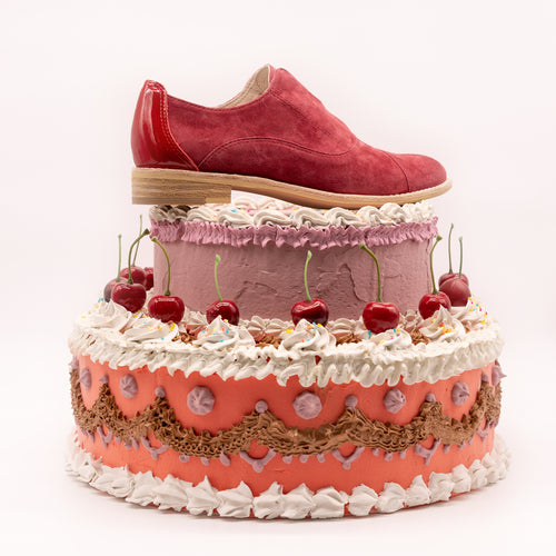 Dark red suede oxfords sitting on top of cake