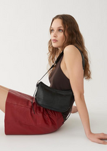 Load image into Gallery viewer, Model wearing black leather shoulder bag and red leather skirt