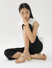 Load image into Gallery viewer, woman wearing black and white outfit with gold heeled sandals