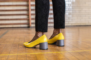 Model wearing Yellow leather pump with chunky grey heel.