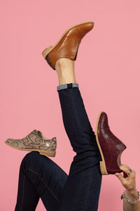 Model wearing and holding Oxblood wine leather embossed oxford, Cognac Tan oxford, and Tan snakeskin oxford