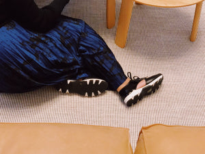 Model wearing Black leather & black patent lace-up urban sneaker.