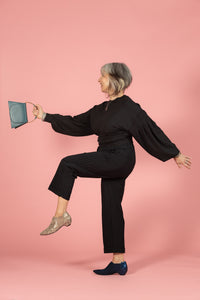 Model holding a handbag wearing Tan Snakeskin bootie and Blue suede and leather bootie