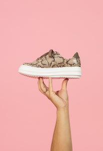 Tan snakeskin chunky sneaker held by model